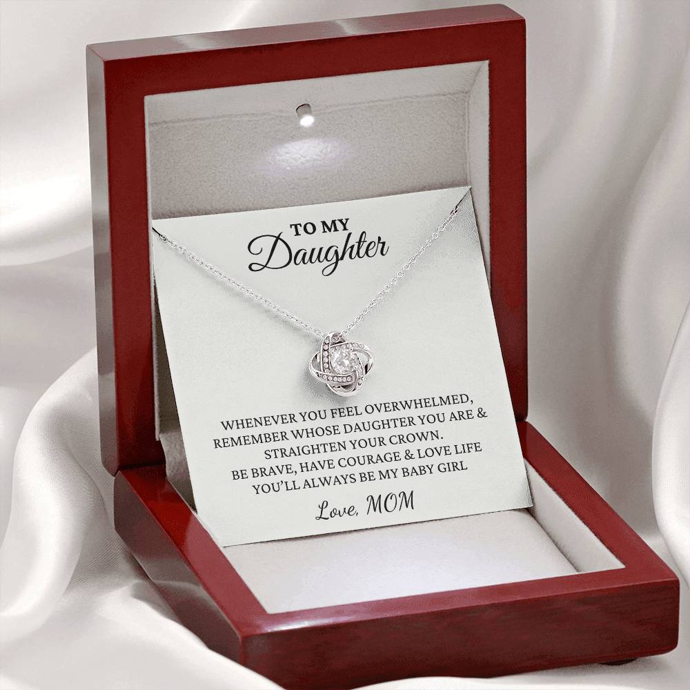 A Love Knot Pendant Necklace displayed in an open red gift box with a white or yellow gold setting and a round cut cubic zirconia stone.