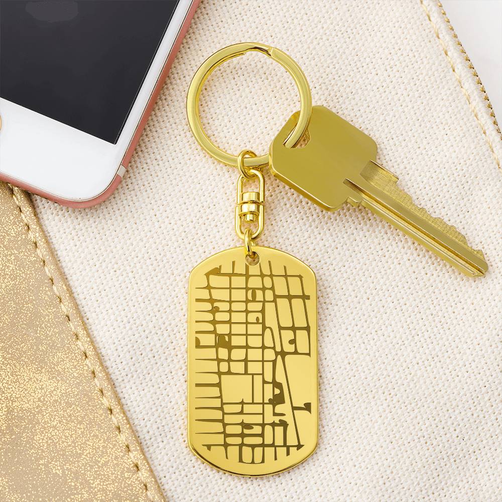 Gold keychain with a map design on a beige surface next to a smartphone.