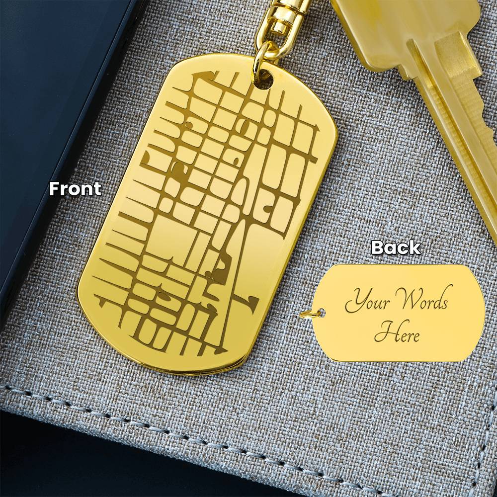 Gold dog tag with engraved design on front and customizable text on back, placed on a textured surface.